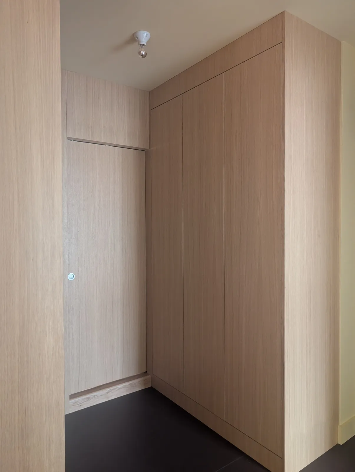 Garderobe i eikefinér tilpasset en vegg med fremspring, med fronter som går helt opp til taket