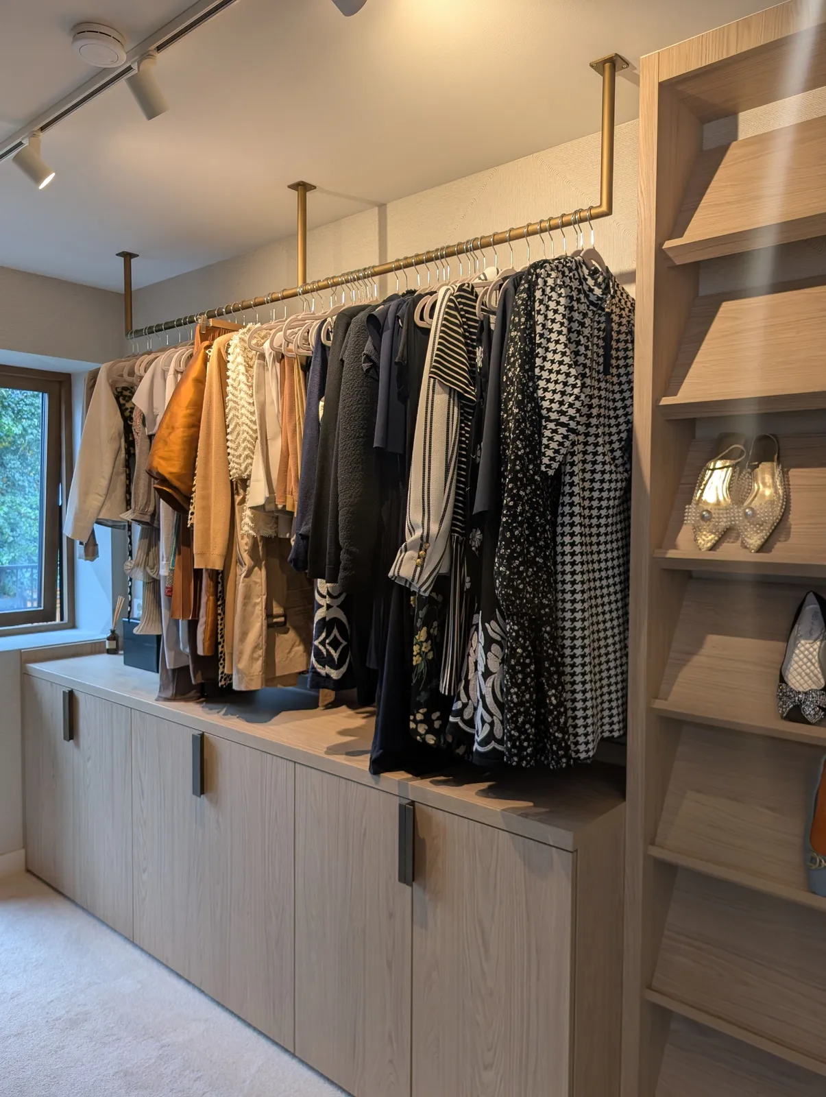 Walk-in-garderobe i eikefinér med åpen hengestang, skuffer og hyller langs veggen